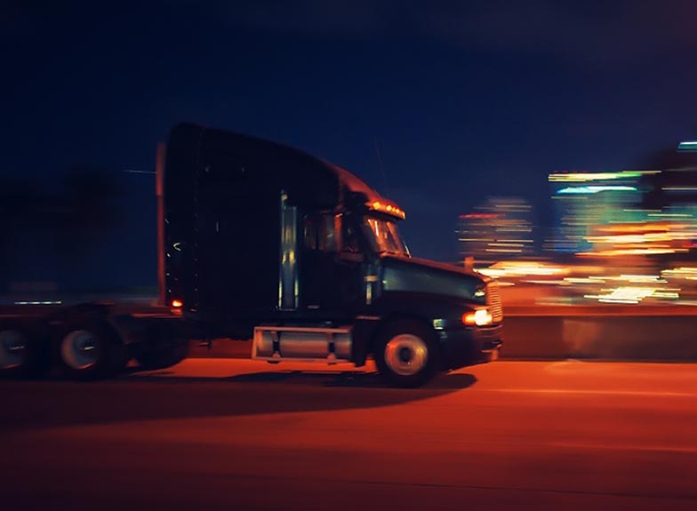 Image of a truck driving at night, slowed to show motion