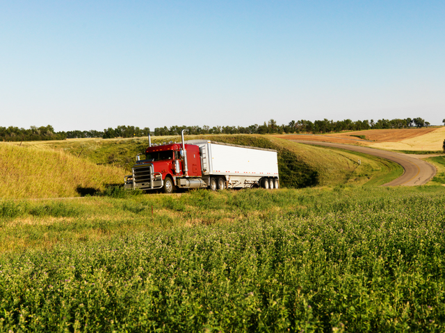 image of a red and white truck driving through a field