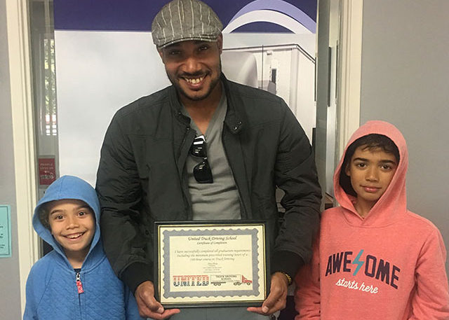 Image of Reynaldo A with his kids holding his CDL certificate