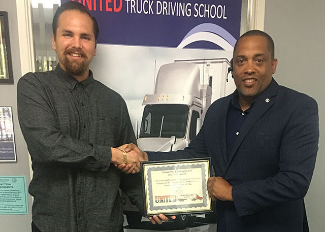 Image of Andres C shaking hands with another man while holding CDL certificate