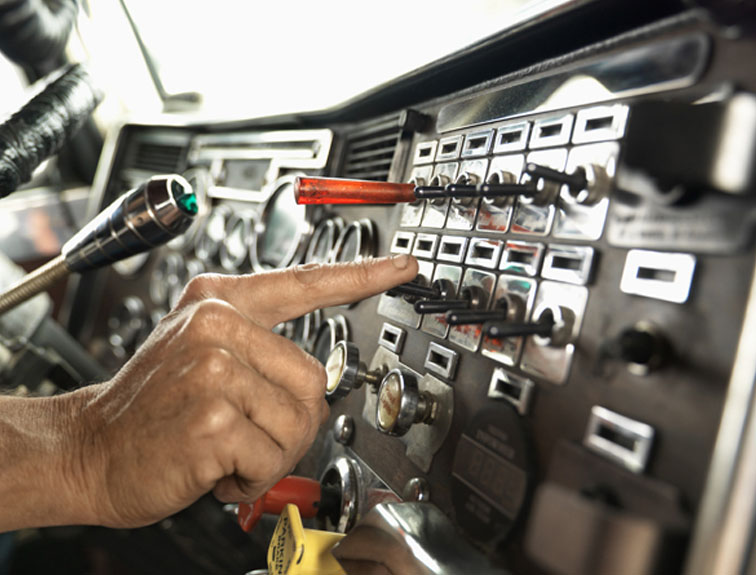 Image of person pushing button on a semi control panel.