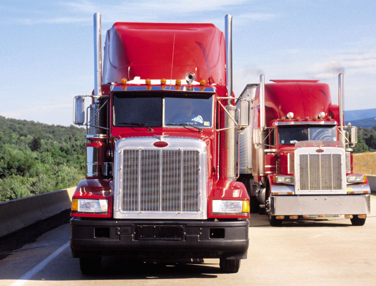 Image of two red semis driving next to each other down the highway