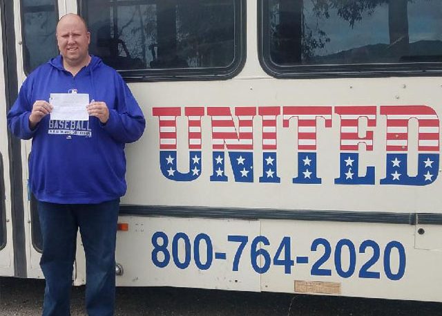 Image of United grad with certificate in front of United bus