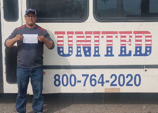 Image of Michael Eder with certificate in front of United bus