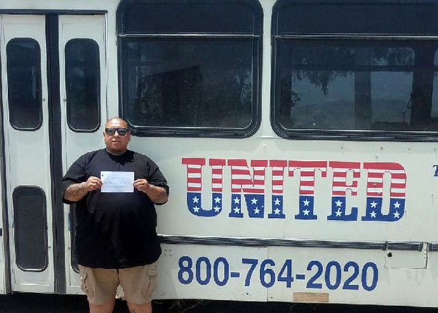Image of Alejandro V with certificate in front of United buss