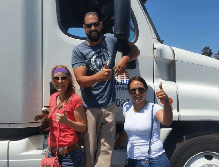 Three truckers posing in front of semi truck cab
