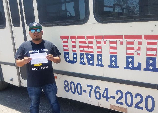 Image of Samir L with certificate in front of United bus