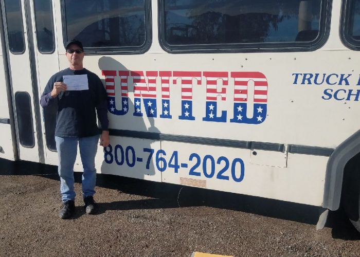 Image of Keith Payfer with certificate in front of United bus