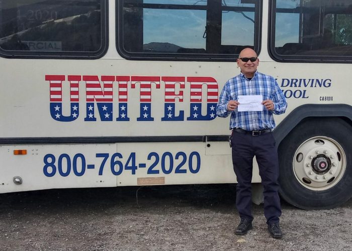 Image of Ralph Rico with certificate in front of United bus