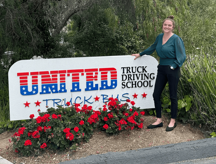 Photo of Sarah Northup in front of United Truck Driving School's Sign