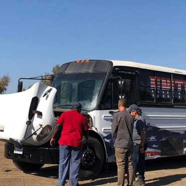 United Truck Driving School bus. Instructors standing at the open hood of the bus.