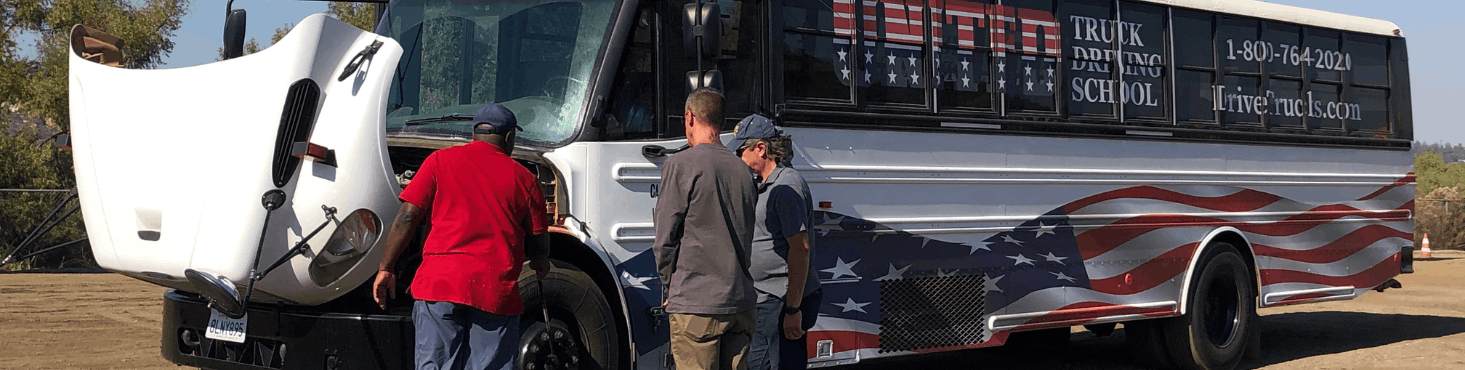 United Truck Driving School bus. Instructors standing at the open hood of the bus.