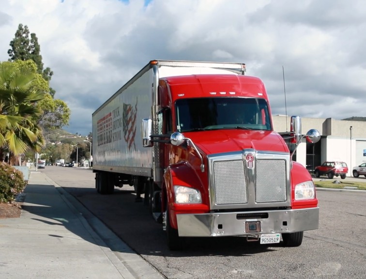 Front view of red United Truck Driving School semi truck driving on a city street