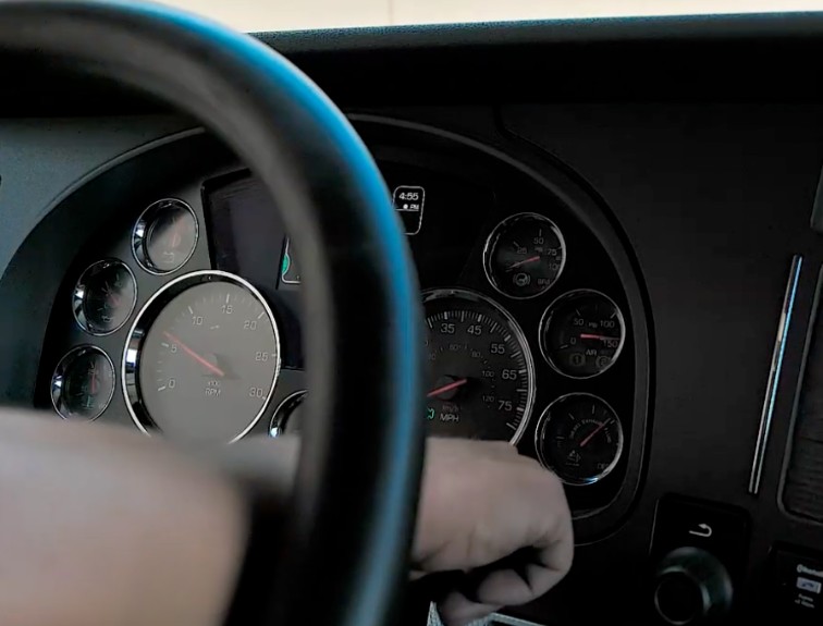Closeup of semi truck gages with a hand pointing